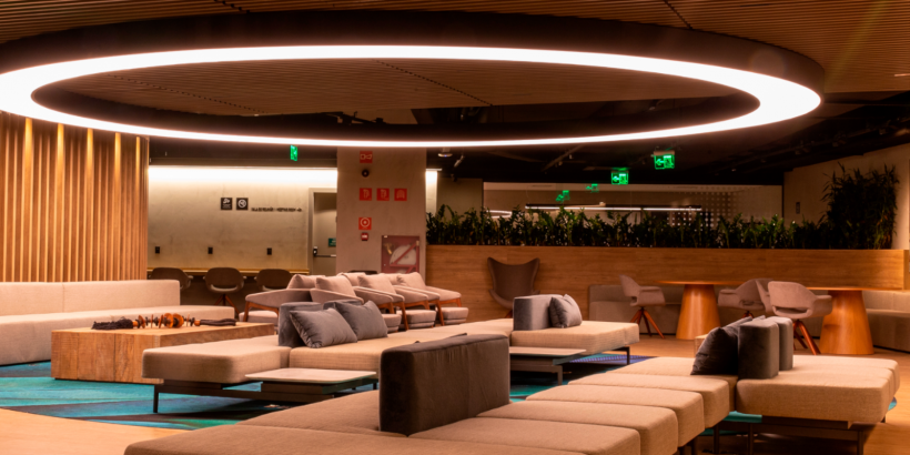 Interior da sala VIP Plaza Premium Lounge no Terminal 2 do Aeroporto de Guarulhos. Um espaço amplo com vários assentos confortáveis e estações de trabalho.